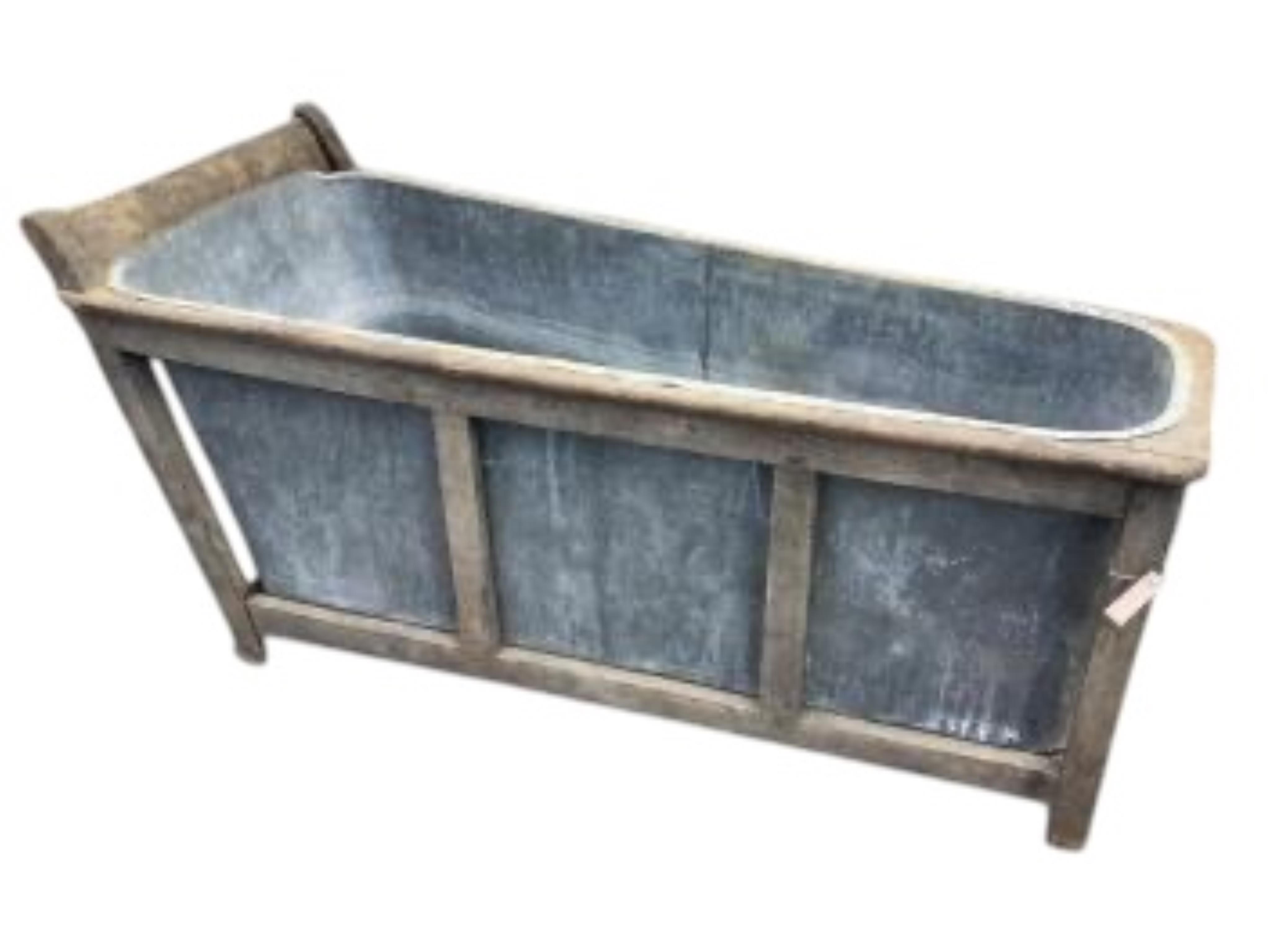 A 19th century French Provincial zinc lined bath with a wooden surround, length 153cm, height 74cm